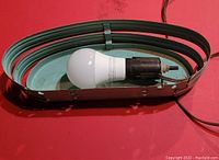 Top-down view showing the LED bulb installed in the black socket within the teal metal curved housing of the wall sconce light.