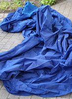 Large blue dust cover folded and placed on the ground outside, showing the fabric material and size.