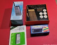 Overview photo showing two walkie talkies in boxes and one solar radio in box on a red surface