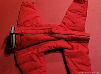 Full view of the red winter dog jacket showing the zipper front and quilted material.