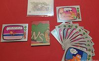 Photo showing multiple Simpsons trading cards with cartoon scenes and dialogue, plus some temporary tattoos partially visible underneath.