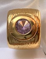 Close-up view of the wide band ring showing texture on the sterling silver and central round amethyst gemstone.