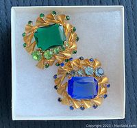 Two vintage gold-tone brooches with large rectangular stones and smaller rhinestones on gold twisted ribbon frames.
