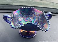 Front and side view of Northwood carnival glass bon bon dish showing iridescent fruits and flowers pattern, ruffled edge, pedestal base, and handles.