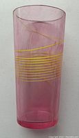 Full view of the pink cylindrical vase with yellow swirl and horizontal stripes.
