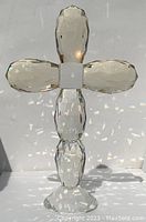 Front view of a clear multifaceted crystal cross showing prism light reflections and faceted base.