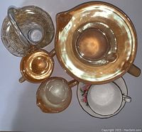 Photo showing all items arranged from a top view, displaying the reflective amber Carnival Glass pieces, floral teacup and clear glass basket