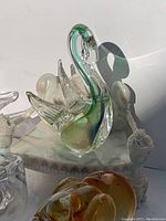 Photo showing the green and clear glass swan figurine with detailed wings and curved neck beside the other glass pieces.