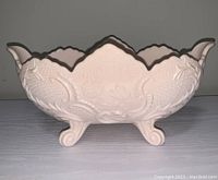 Side view of the pink milk glass bowl showing scalloped edges and floral embossed design.