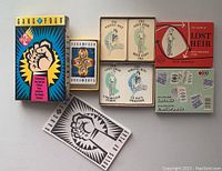 Photo of Gang of Four and Lost Heir card game boxes, open cards, and rules, laid flat showing card faces and packaging.