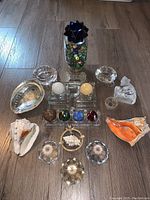 Full view of all items arranged on wooden floor including crystal cat, jar of marbles, shells, and decorative glass pieces