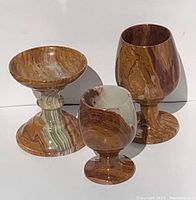 Front view of three onyx/marble glasses and pedestal bowl showing natural veining and multi-color patterns