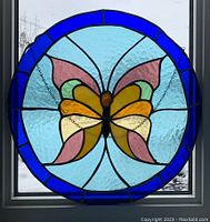 Front view of stained glass butterfly with blue border and colorful wings