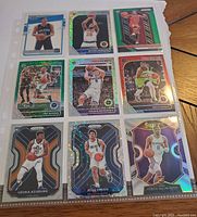 Photo of nine basketball cards including rookies, holographic, rare and cracked ice finishes arranged in a plastic sleeve on a flat surface