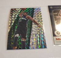 Holographic card showing Giannis Antetokounmpo dunking in black Bucks jersey, with shiny prismatic effect.