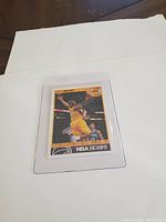 Basketball card of Kobe Bryant in yellow Lakers jersey mid-air, NBA Hoops card