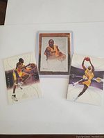 Three Kobe Bryant basketball trading cards laid out on white background.
