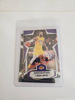 LeBron James Rookies & Stars basketball card showing him dribbling in Lakers yellow uniform, in a protective sleeve.