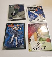 Photo showing all four Luka Doncic basketball cards laid out on a white surface including a Platinum Cuts autograph card