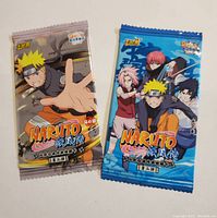 Two sealed Naruto collectible card packs side by side on a white background showing front packaging with distinct character illustrations.