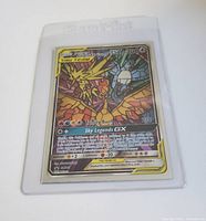 Front view of the full art Pokemon GX Tag Team card showing Moltres, Zapdos, and Articuno in protective sleeve.