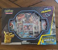 Front view of sealed Pokemon Detective Pikachu Greninja-GX Case File showing promo card and pin through window.