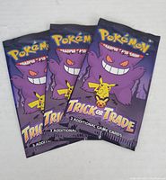 Front view of three sealed Pokémon Trick or Trade booster packs with Gengar and Pikachu on the packaging.