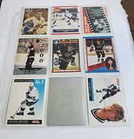 Front view of all nine Wayne Gretzky hockey cards arranged in a 3x3 grid in a plastic sleeve sheet, showing various action shots, portraits, stats, and a hologram card.