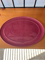 Top-down view of oval Denby serving platter showing deep reddish-purple speckled ceramic surface and raised edge.