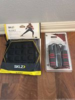 SKLZ Slidez in packaging and BCG Speed Rope in packaging on a wood floor