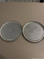 Two Pampered Chef tart pans with fluted edges and textured bottoms on a table, both showing some scratches.