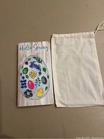 Closed journal with illustrated spring cover and natural-colored muslin bag beside it on a flat surface.