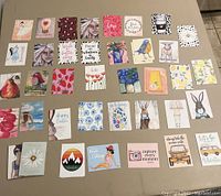 Photo showing 35 assorted planner tip-in cards laid out flat, displaying various colorful illustrations and inspirational text, suitable for use in planners or journals.