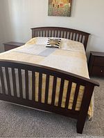 Queen mission style bed frame assembled with bedding on carpeted floor, showing vertical slat headboard and footboard with scratches visible.