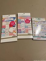Three packs of Recollections Paper Studio stickers shown from front, including motivational and decorative sticker themes, unopened or lightly used