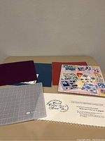 Scrapbooking supplies including colored sheets, cutting board, layout guide, and cutting pattern sheets