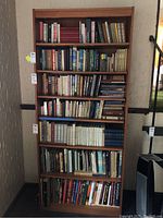 Front view of wooden bookcase filled with books, showing seven shelves.