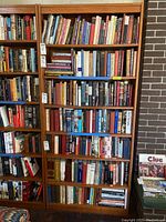 Front view of the tall wooden bookcase filled with books on all shelves.
