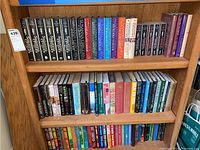 Bookshelf with three shelves holding various fiction novels primarily by Susanna Gregory and other authors.