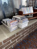 Two plastic bins filled with CDs labeled 'Classical' and 'Misc/ Mitch Miller' positioned next to each other.