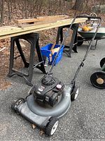 Side view of Craftsman lawn mower showing handle, blade deck, wheels, and parts of the engine.