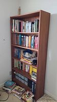 Full view of wooden bookshelf filled with various books and storage boxes showing overall size and condition.