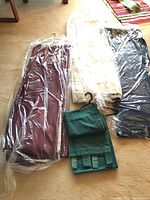 View of all drapery panels laid on floor, showing burgundy, beige, blue panels with tiebacks, and green panel folded.