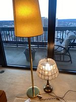 Photo of both lamps together; gold tone floor lamp with fabric shade and antique brass table lamp with wireframe stained shade, showing height and condition