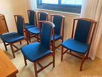 Six teak chairs arranged in room, front view