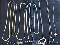 Eight assorted chain necklaces laid out on dark background