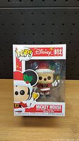 Front view of boxed Funko Pop! figure of Christmas Mickey Mouse showing figure inside and box details.