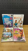 Front covers of the four Nintendo Wii fitness games: Just Dance 3, EA Sports Active, Summer Sports, Zumba Fitness Party, showing cover art and rating labels.