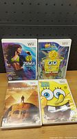 Front covers of four Nintendo Wii game cases: Zumba Fitness, SpongeBob Atlantis SquarePantis, Jumper, and SpongeBob Lights, Camera, Pants!