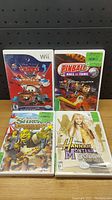 Front covers of the four Nintendo Wii games showing Cars Toon, Pinball Hall of Fame, Shrek the Third, and Hannah Montana titles.
